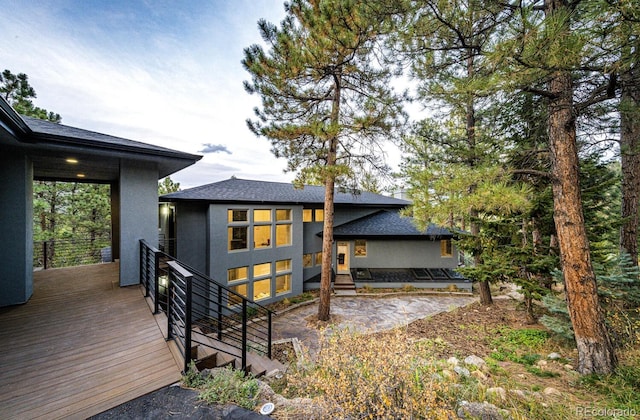 rear view of property featuring a wooden deck and a patio