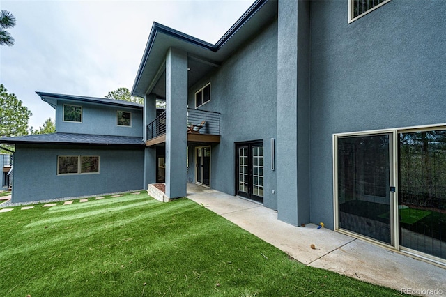 back of property featuring a yard, a patio area, and a balcony