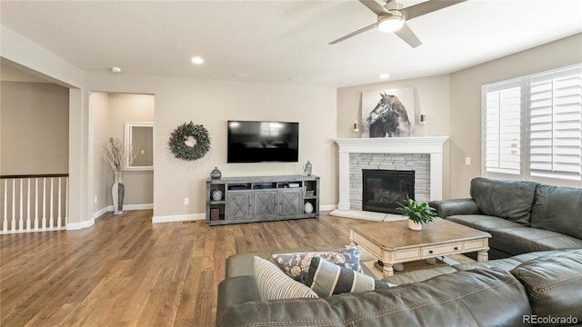 living room with wood finished floors, recessed lighting, a fireplace, a ceiling fan, and baseboards