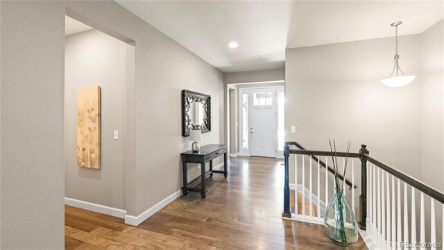 hallway featuring baseboards, an upstairs landing, and wood finished floors