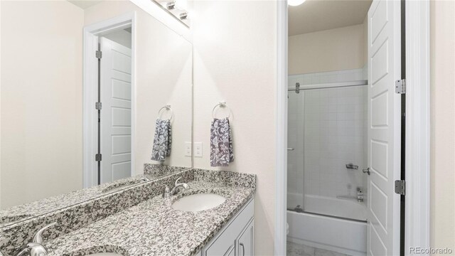 full bath with double vanity, combined bath / shower with glass door, and a sink