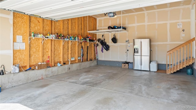 garage featuring white refrigerator with ice dispenser and a garage door opener