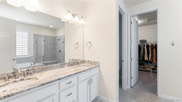 full bathroom featuring a shower stall, double vanity, baseboards, a spacious closet, and tile patterned floors