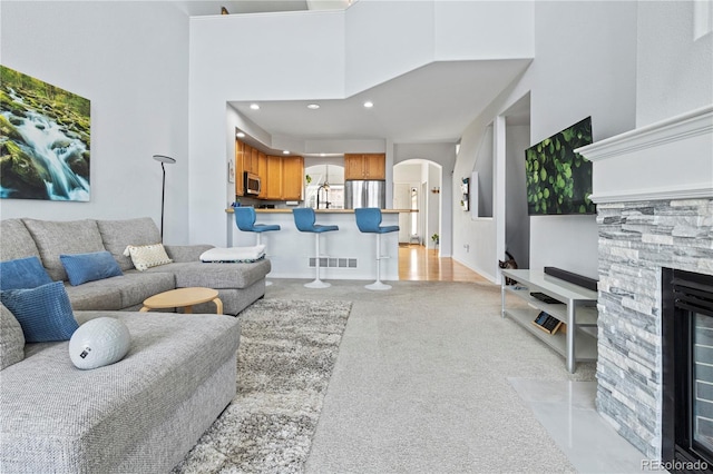3425 W 111th Loop Unit B, Westminster, CO 80031 - living room with arched walkways, a towering ceiling, light colored carpet, recessed lighting, and a stone fireplace