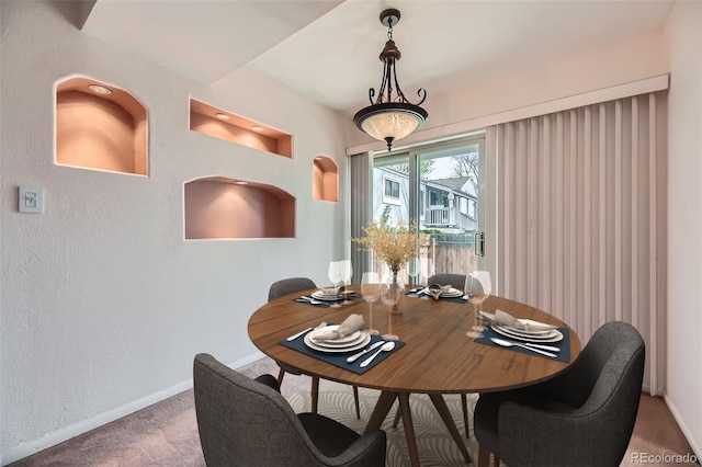 dining space with a textured wall, carpet floors, and baseboards