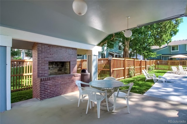 view of patio with outdoor dining space, fence, and an outdoor brick fireplace