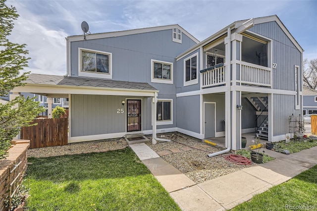 view of front facade featuring stairway, fence, and a front yard