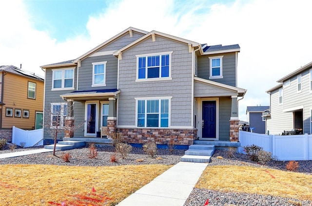 craftsman-style home with stone siding and fence