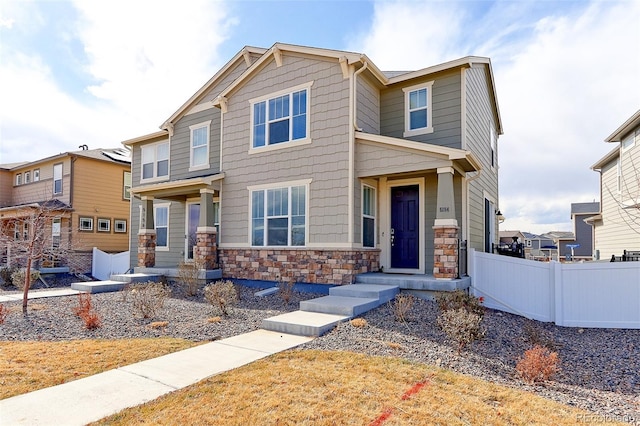 craftsman inspired home featuring stone siding and fence