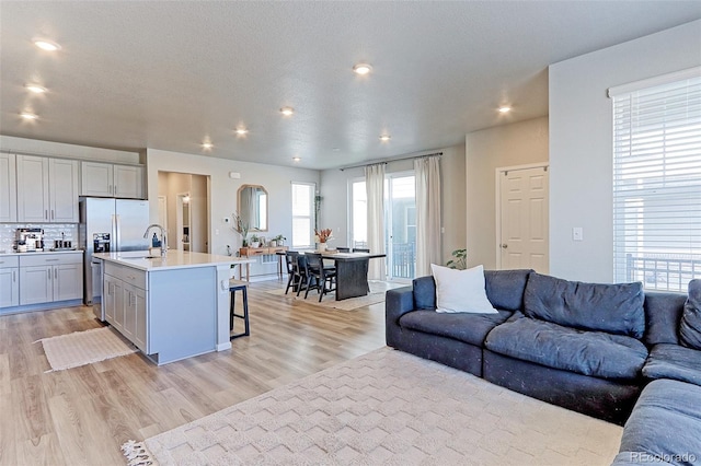 living room featuring light wood-style floors, a textured ceiling, and recessed lighting