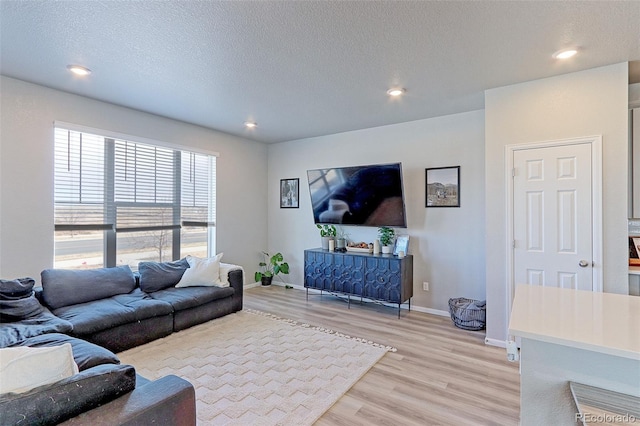 living room with a textured ceiling, light wood-type flooring, baseboards, and recessed lighting