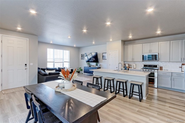 dining area with a textured ceiling, recessed lighting, and light wood-style floors