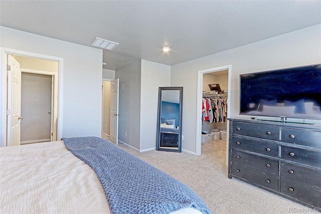 bedroom featuring a textured ceiling, carpet, a walk in closet, and visible vents