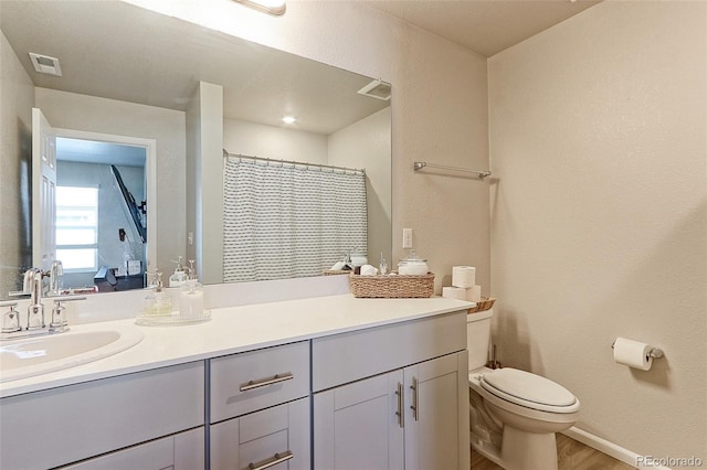 bathroom featuring toilet, visible vents, wood finished floors, and vanity