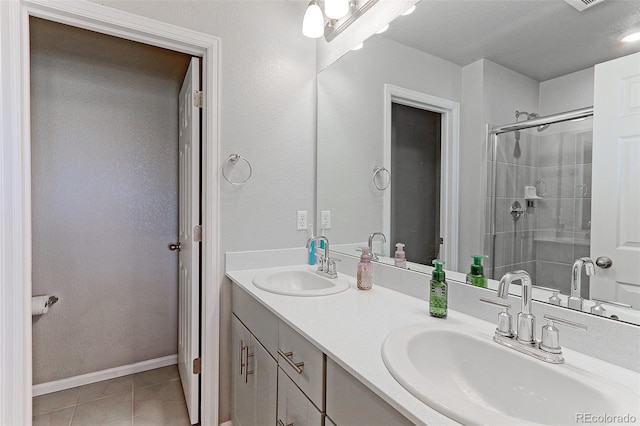 bathroom with double vanity, a stall shower, tile patterned flooring, and a sink