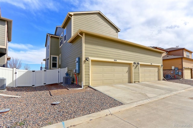 view of home's exterior featuring a gate, central AC, fence, a garage, and driveway