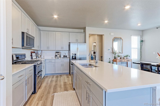5154 Bittercress Rd, Brighton, CO 80640 - kitchen featuring appliances with stainless steel finishes, a sink, light wood-type flooring, light countertops, and backsplash