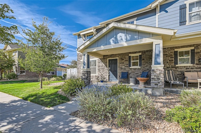 1133 S Richfield St, Aurora, CO 80017 - view of front of property featuring covered porch, stone siding, and a front yard