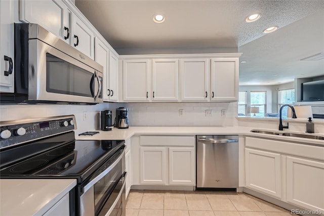 1133 S Richfield St, Aurora, CO 80017 - kitchen with stainless steel appliances, white cabinets, light tile patterned flooring, recessed lighting, and light countertops