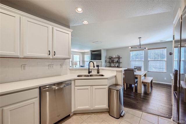 1133 S Richfield St, Aurora, CO 80017 - kitchen with stainless steel dishwasher, a peninsula, white cabinetry, a textured ceiling, and light countertops