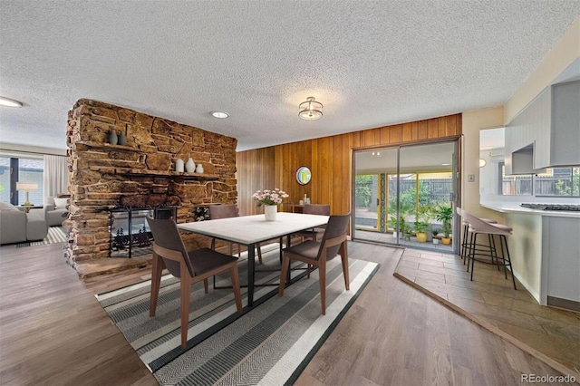 dining area featuring light wood-type flooring, a textured ceiling, plenty of natural light, and a fireplace