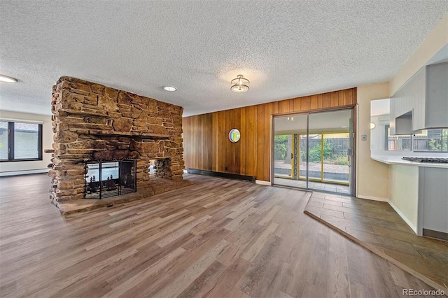 unfurnished living room featuring wood-type flooring, a textured ceiling, plenty of natural light, and a fireplace