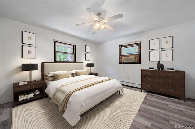 bedroom with baseboard heating, hardwood / wood-style floors, cooling unit, and ceiling fan