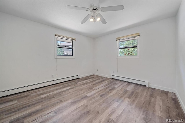 unfurnished room with a wealth of natural light, a baseboard heating unit, and light hardwood / wood-style floors