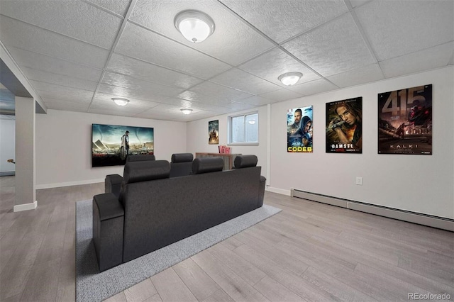 cinema featuring a drop ceiling, light hardwood / wood-style flooring, and a baseboard heating unit