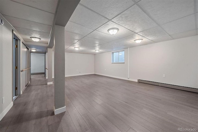 basement with hardwood / wood-style flooring, a drop ceiling, and a baseboard heating unit