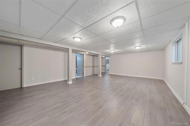 basement with hardwood / wood-style flooring and a paneled ceiling