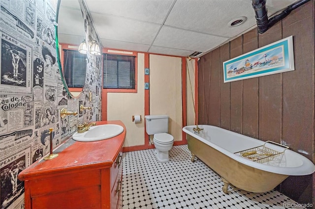 bathroom featuring a tub to relax in, vanity, a paneled ceiling, and toilet