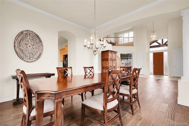 dining space featuring a chandelier, arched walkways, ornamental molding, baseboards, and light wood-type flooring