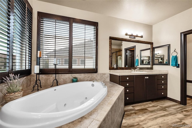 bathroom featuring a jetted tub, vanity, a shower stall, and baseboards