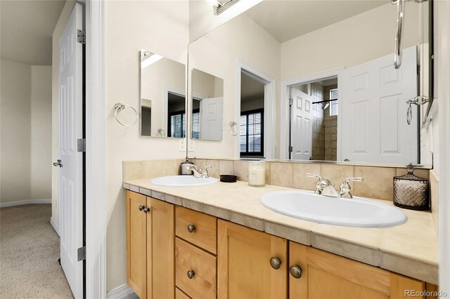 bathroom featuring double vanity, baseboards, and a shower
