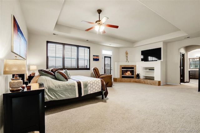 23965 E Kettle Pl, Aurora, CO 80016 - carpeted bedroom with a raised ceiling, arched walkways, a tiled fireplace, and a ceiling fan