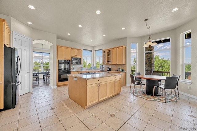 23965 E Kettle Pl, Aurora, CO 80016 - kitchen featuring black appliances, light brown cabinetry, recessed lighting, a center island, and healthy amount of natural light