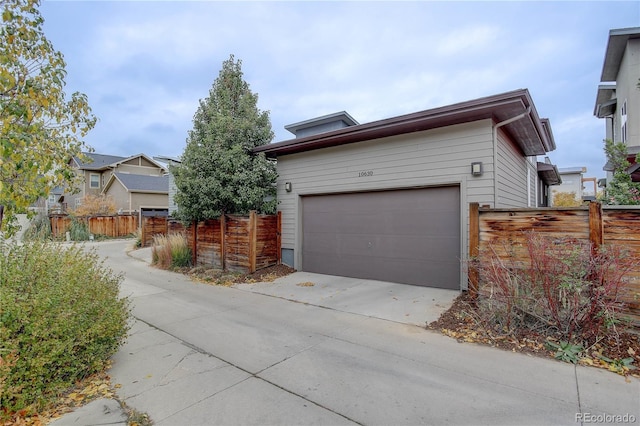 view of home's exterior featuring concrete driveway, a garage, and fence