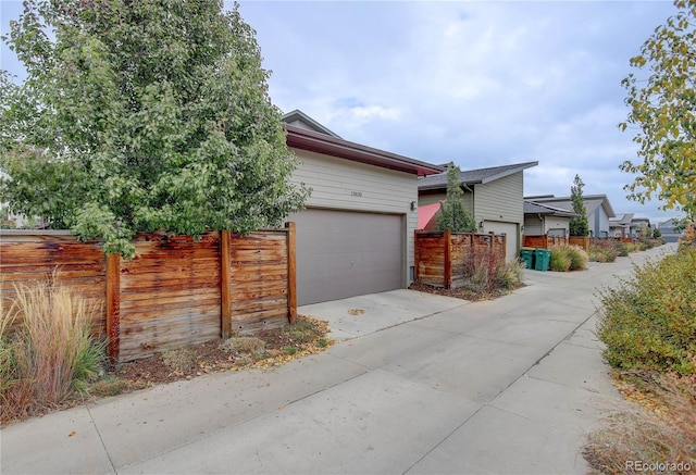 view of home's exterior with an attached garage, concrete driveway, and fence