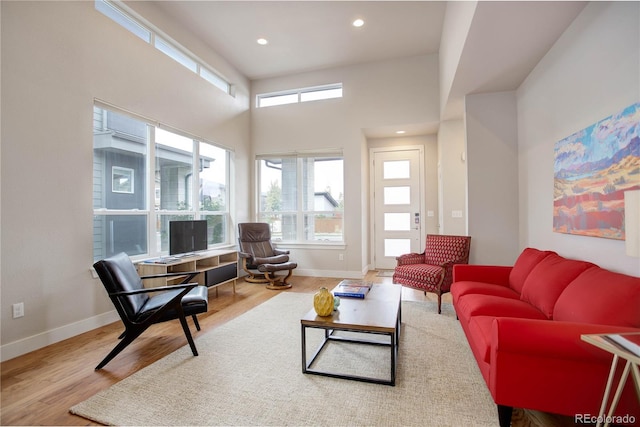 living area featuring a towering ceiling, recessed lighting, baseboards, and wood finished floors