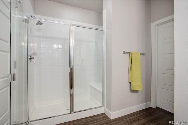 full bathroom featuring a stall shower, baseboards, and wood finished floors