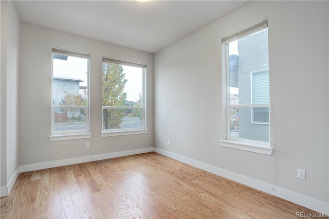 unfurnished room with visible vents, baseboards, and wood finished floors