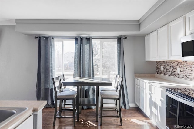 kitchen with dark hardwood / wood-style flooring, backsplash, electric range, and white cabinets