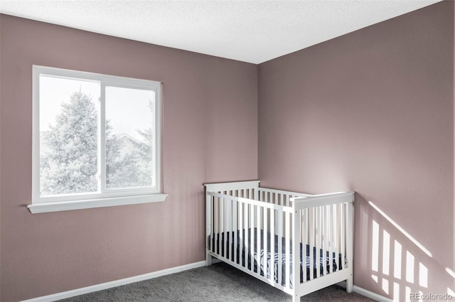 unfurnished bedroom featuring a nursery area, a textured ceiling, and carpet flooring