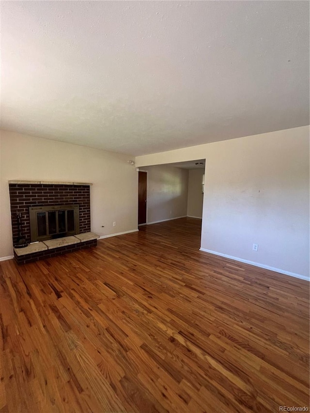 11812 E Alaska Ave, Aurora, CO 80012 - unfurnished living room with wood finished floors and a fireplace