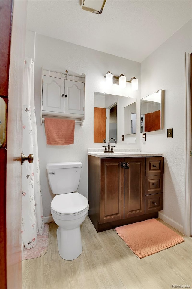 bathroom featuring wood-type flooring, vanity, and toilet