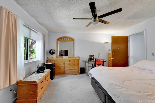 bedroom featuring ceiling fan, light colored carpet, and a textured ceiling