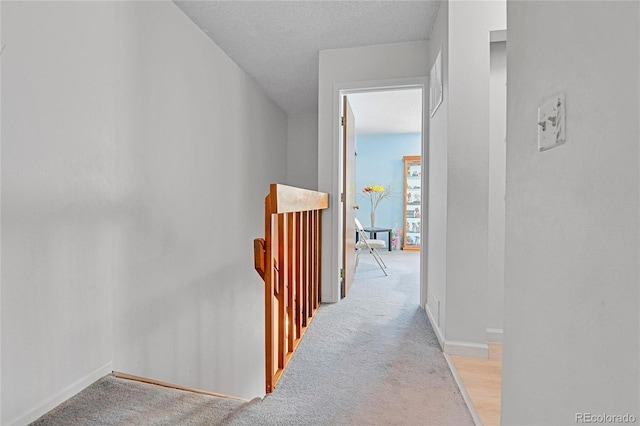 corridor with light carpet and a textured ceiling