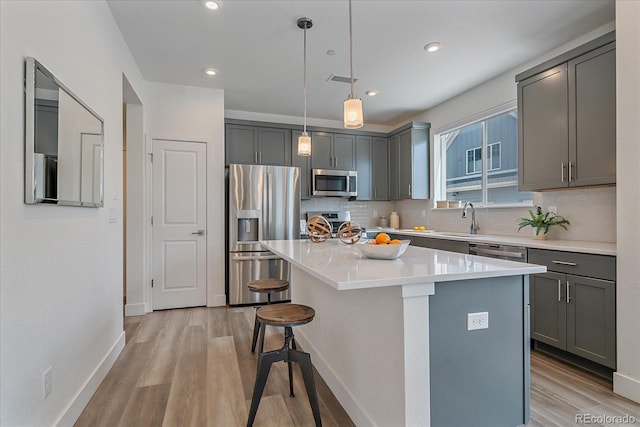 6106 W 28th Ct, Edgewater, CO 80214 - kitchen featuring appliances with stainless steel finishes, gray cabinetry, a kitchen bar, light wood finished floors, and recessed lighting