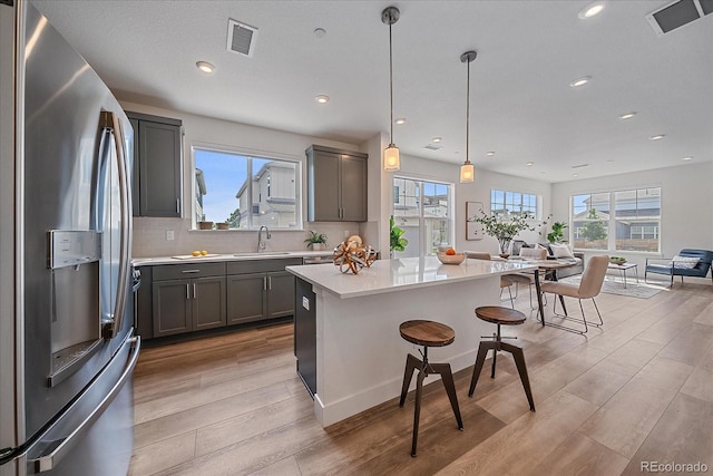 6106 W 28th Ct, Edgewater, CO 80214 - kitchen with stainless steel refrigerator with ice dispenser, light wood-style flooring, light countertops, a kitchen breakfast bar, and recessed lighting